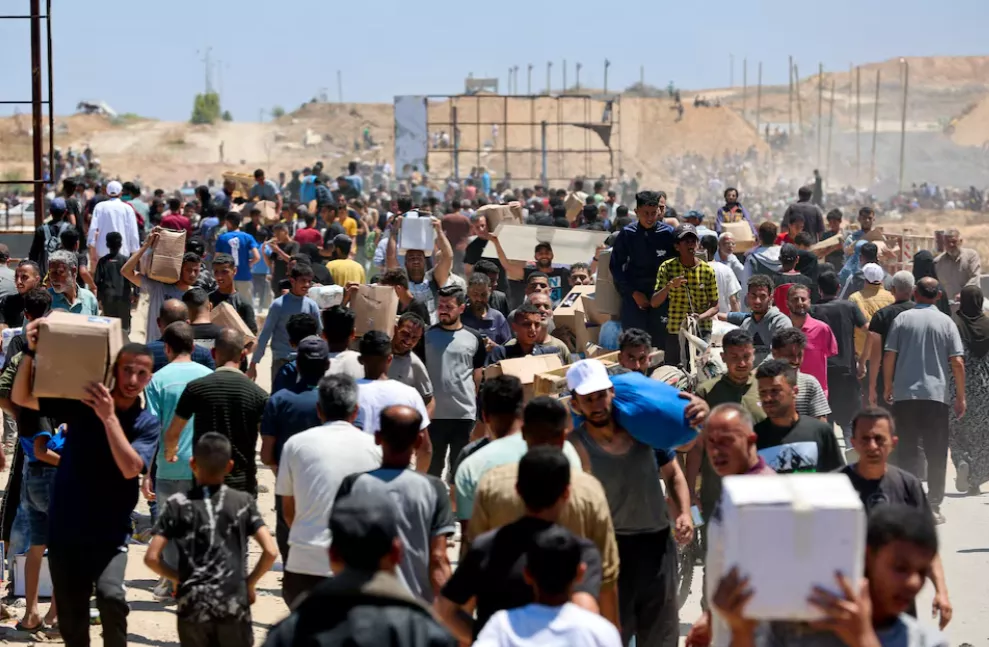 Palestinos carregam suprimentos de ajuda que receberam da Fundação Humanitária de Gaza, apoiada pelos EUA, no centro da Faixa de Gaza, em 29 de maio de 2025